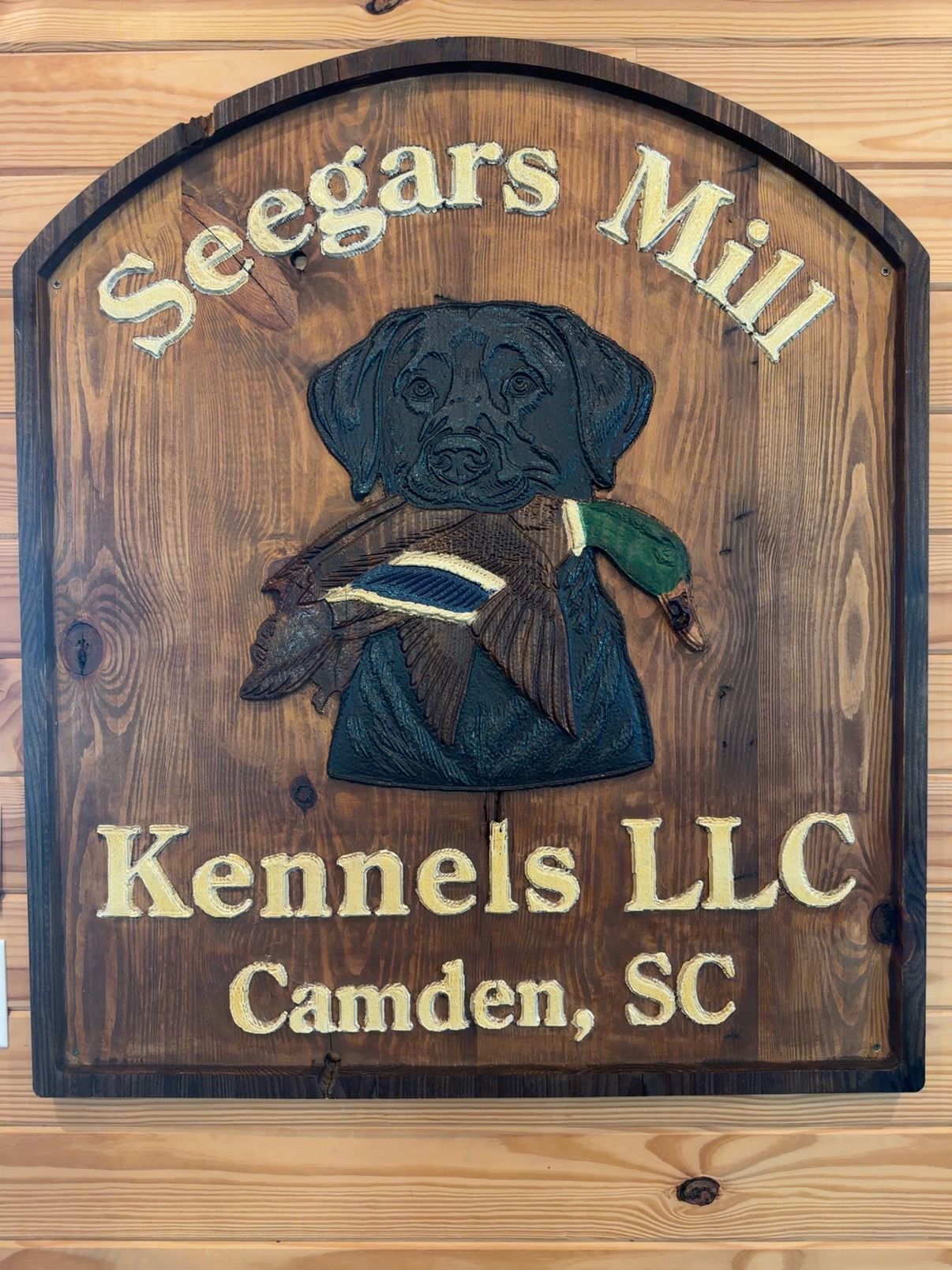 Carved wooden Seegars Mill Kennels LLC sign with retriever and duck